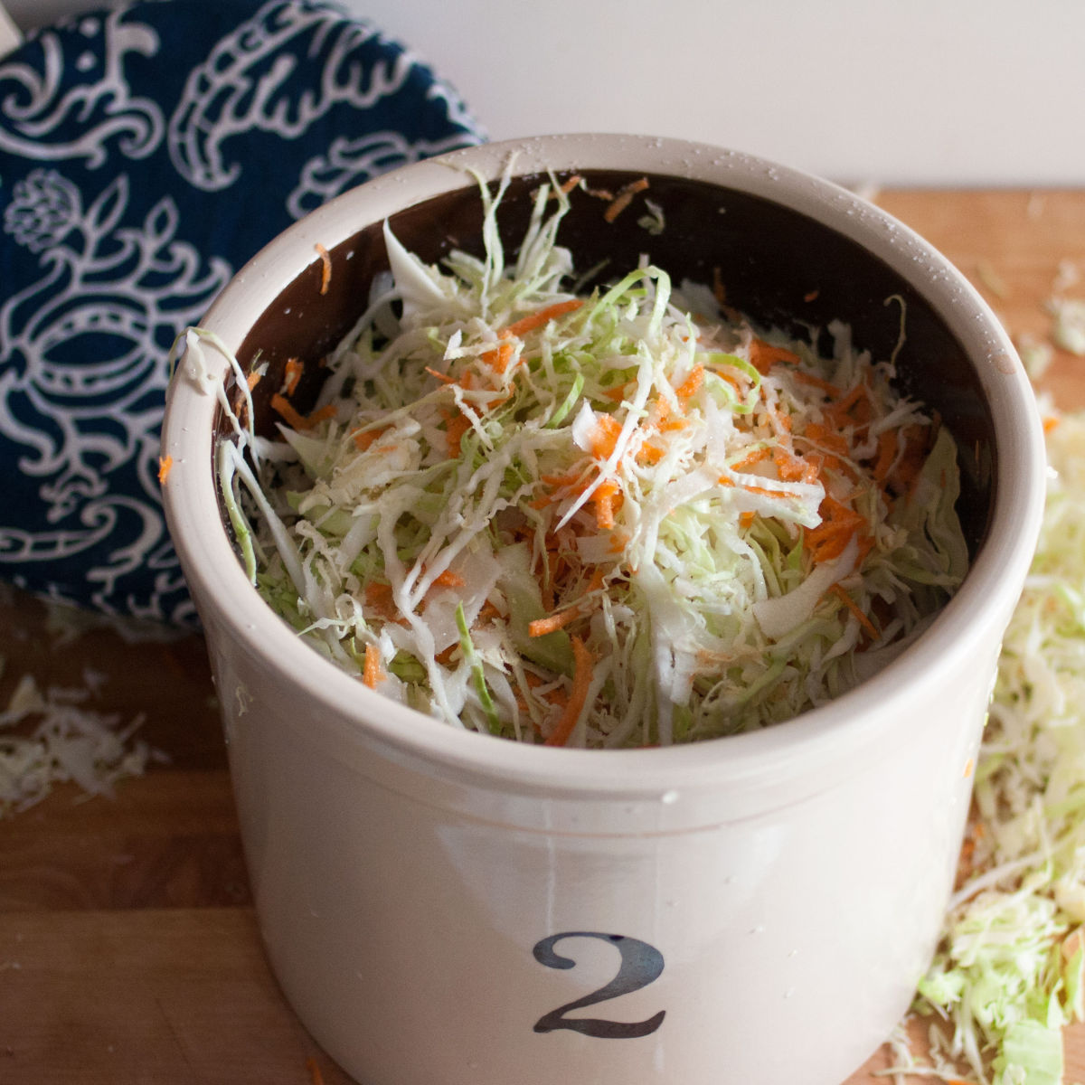 Shredded cabbage and carrot in a crock Kirby & Kraut