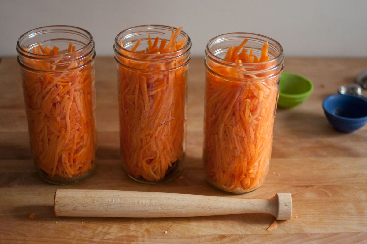 Packing carrots into mason jars for pickling Kirby & Kraut